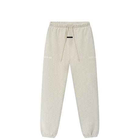 Light beige heather sweatpants with an elastic waistband, beige drawstrings, and subtle white text graphics on the upper thighs, shown against a plain white background.