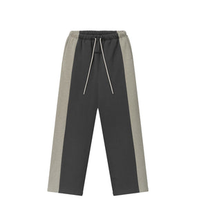 A pair of color-blocked sweatpants in dark gray and light gray, featuring a white drawstring, shown against a plain white background.